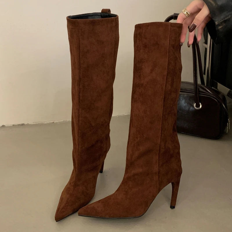 Botas altas de antelina camel de pie con un bolso detrás