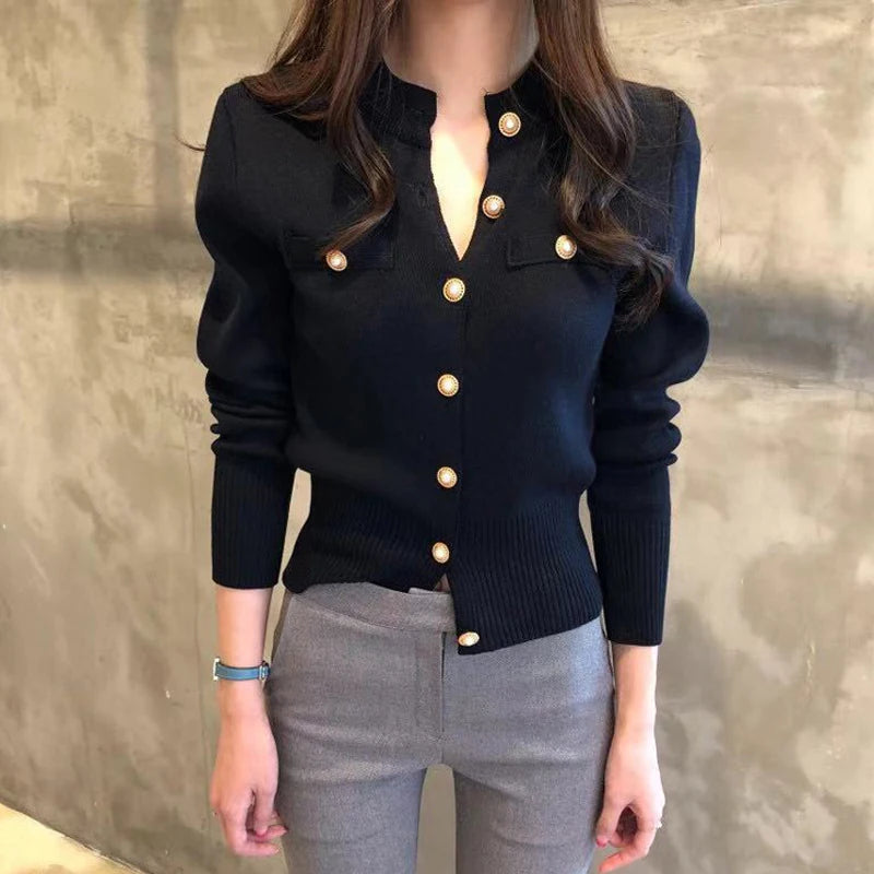 Mujer con la chaqueta marino abrochada y pantalón gris, con los botones dorados y el cuello mao a la vista