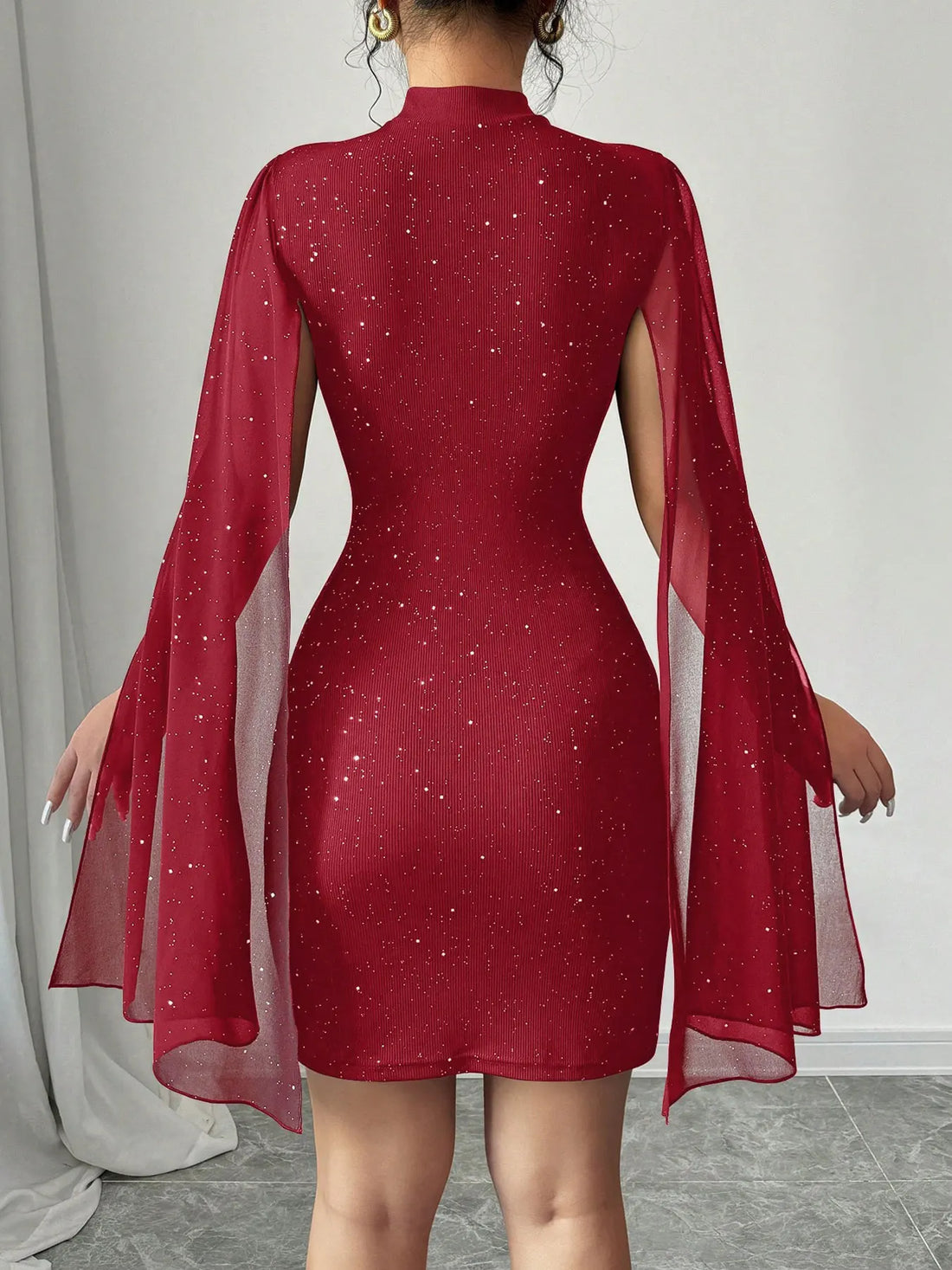 El vestido mini rojo con los dos brazos extendidos, mostrando las mangas capa de gasa