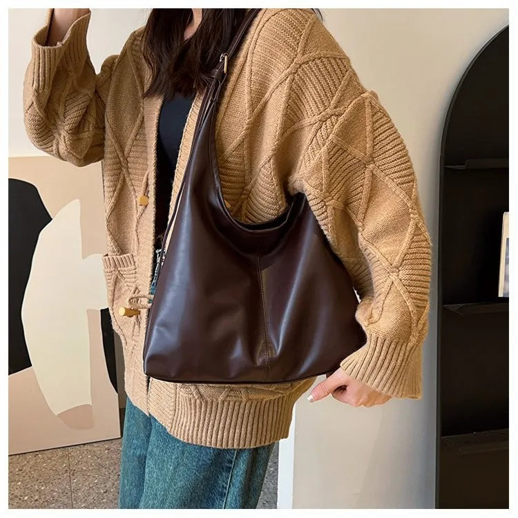 Detalle del tote chocolate al hombro, con una chaqueta de ochos camel y vaqueros
