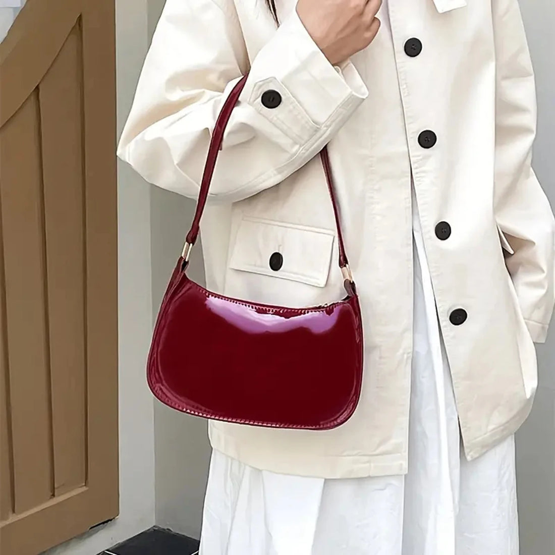 Bolso baguette burdeos al hombro sobre una sobrecamisa blanca