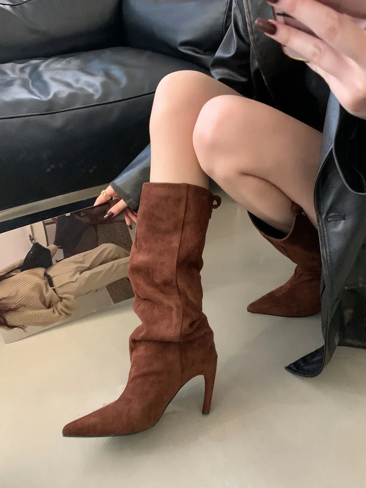 Las botas de antelina camel puestas, sentada, con una cazadora de piel negra